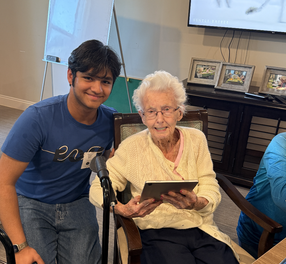 Ishaan and a resident celebrate her first successful use of an iPad with a proud photo together.