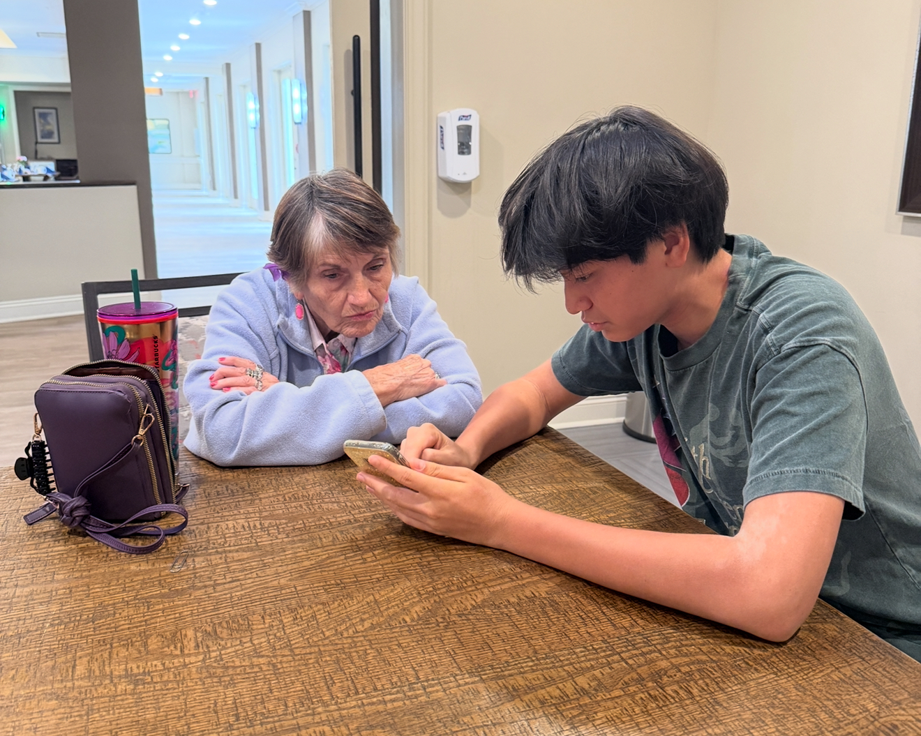 A volunteer patiently guides a senior through using her phone during a Project Tech session.