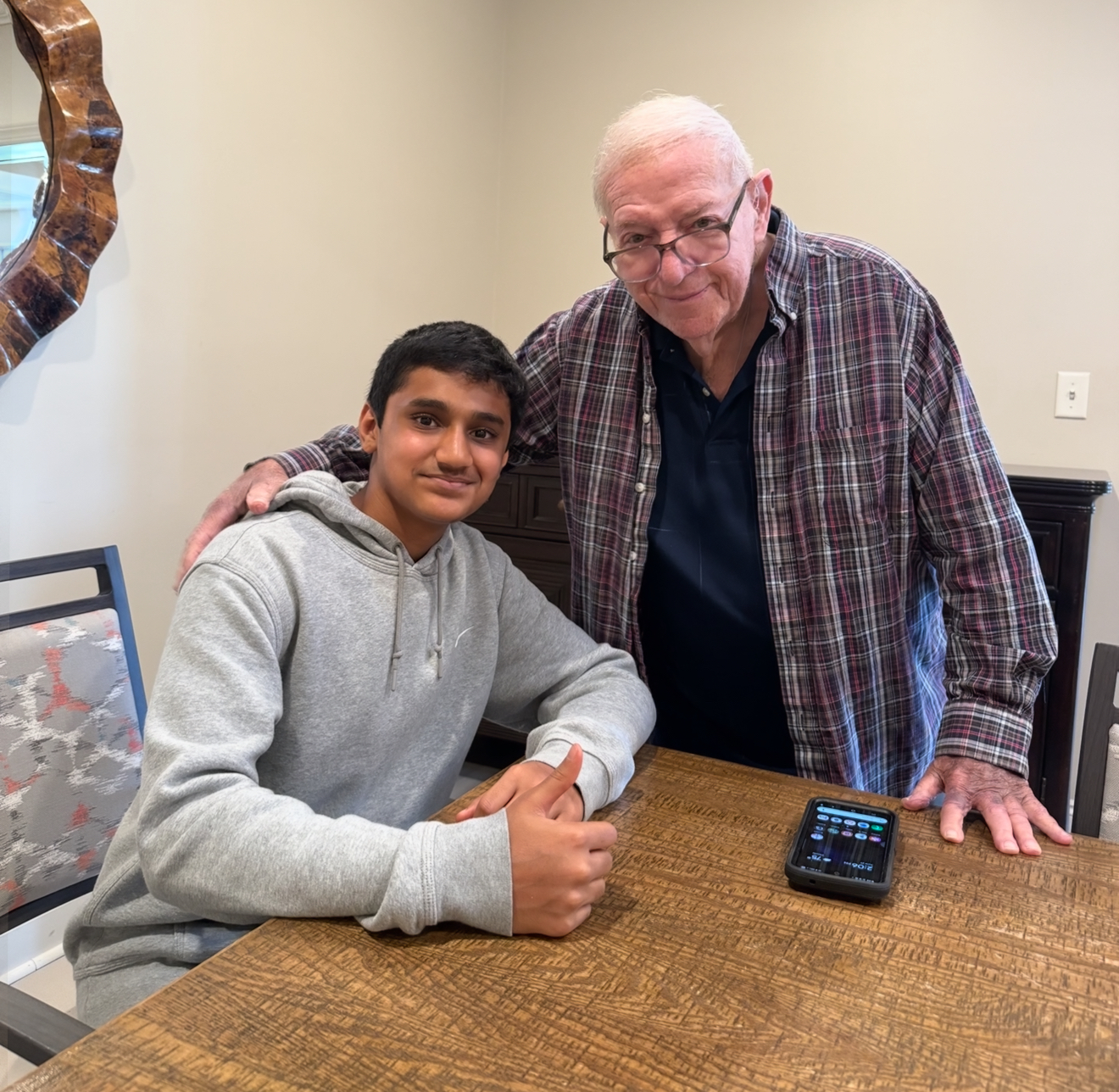 A volunteer shares a friendly moment with a senior after helping with smartphone basics during a tech session.